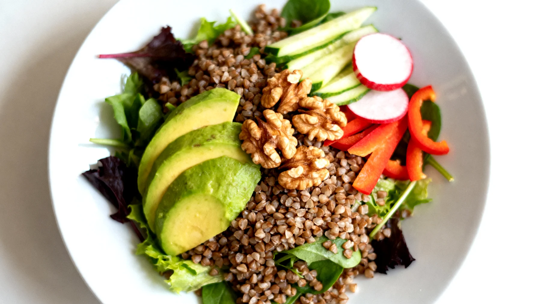 Insalata di grano saraceno con avocado, noci e verdure crude"